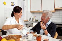 caregiver serving food to elderly woman