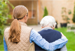 caregiver assists the elderly woman back to her home